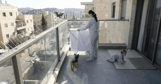 דוקרנים נגד יונים | מה יותר מלכלך מגשם ראשון? צואת יונים על הכביסה - אישה תולה כביסה במרפסת